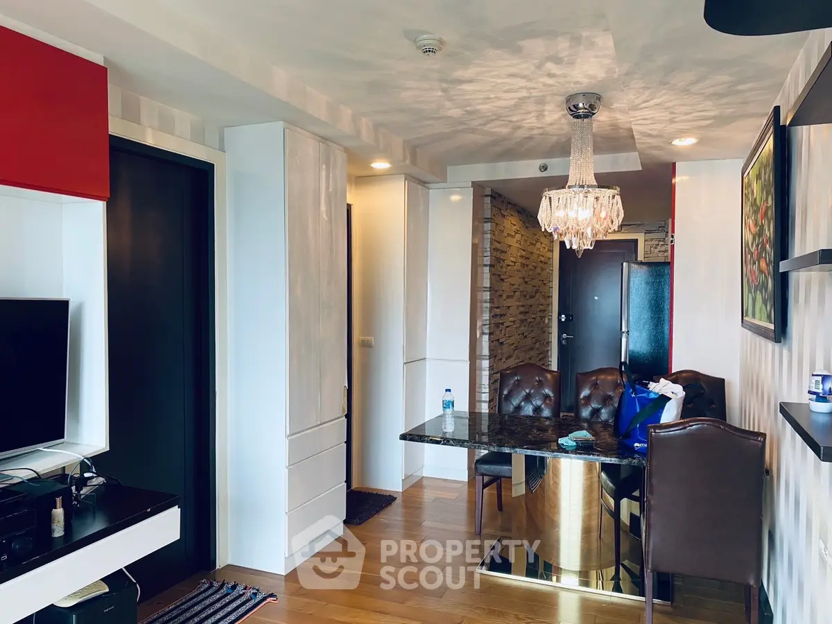 Stylish modern living room with elegant chandelier and dining area in a contemporary apartment.