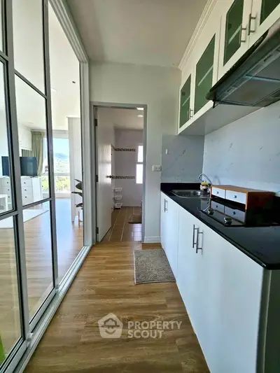 Modern kitchen with sleek cabinets and open layout leading to a bright living area with scenic views.