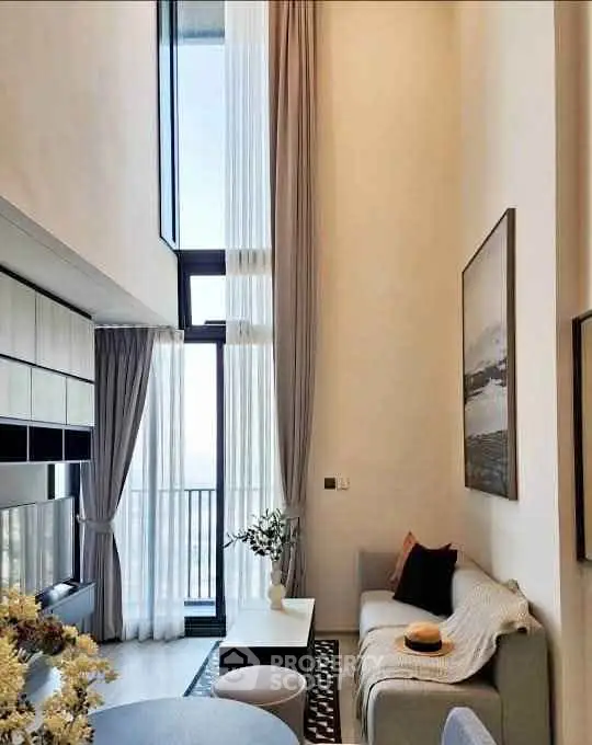 Luxurious high-ceiling living room with modern decor and large windows offering natural light.