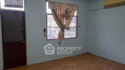Spacious room with wooden flooring and natural light, featuring a window fan and air conditioning.
