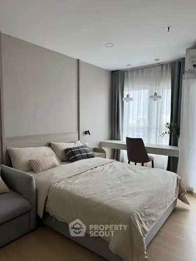 Modern bedroom with cozy bed and study area, featuring natural light and elegant decor.
