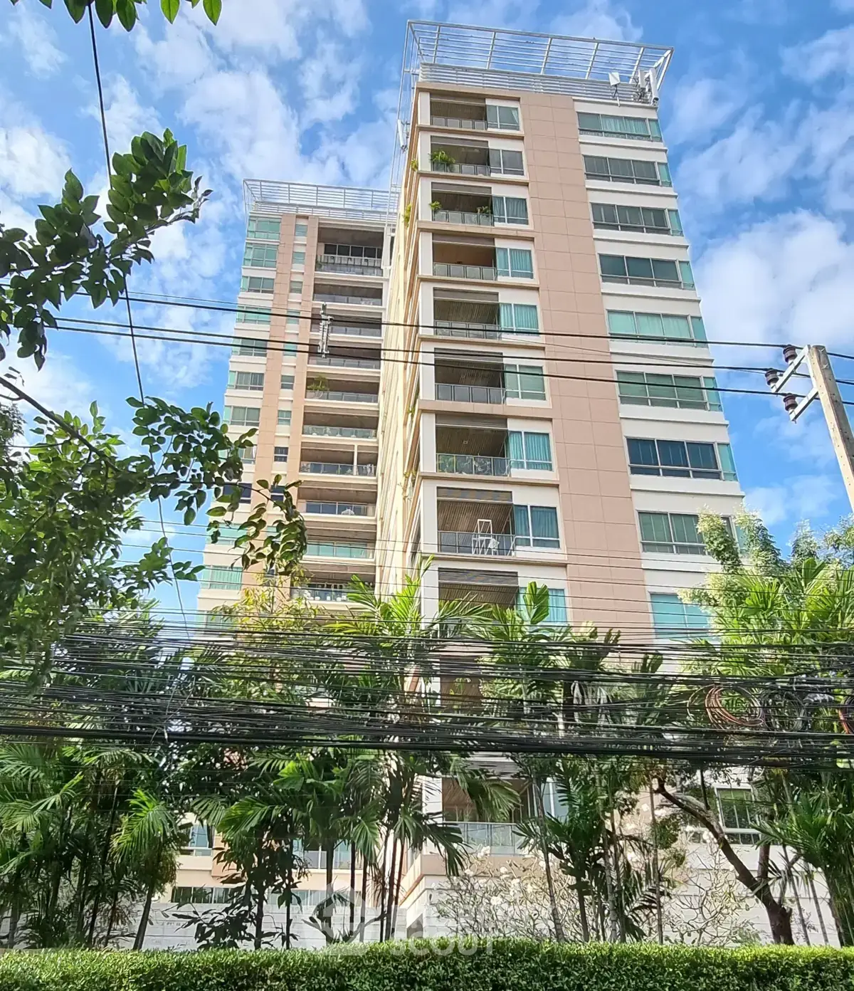 Modern high-rise building with lush greenery and clear blue sky