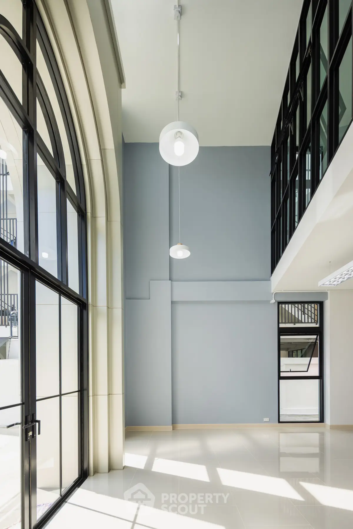 Spacious modern interior with high ceilings and large windows, perfect for natural light.