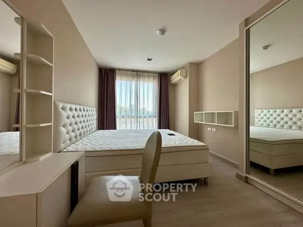 Spacious bedroom with modern furniture and large window offering natural light.