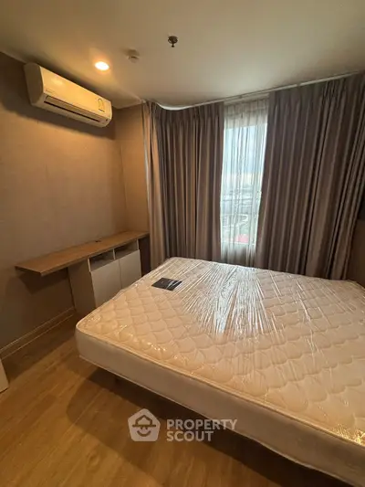 Cozy bedroom with natural light, featuring a comfortable bed and air conditioning for a relaxing retreat.