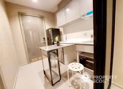 Compact modern kitchen with sleek white cabinetry, built-in oven, and a minimalist breakfast bar, perfect for urban living.