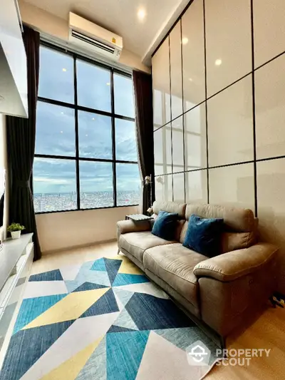 Modern living room with large windows and city view, featuring stylish sofa and geometric rug.