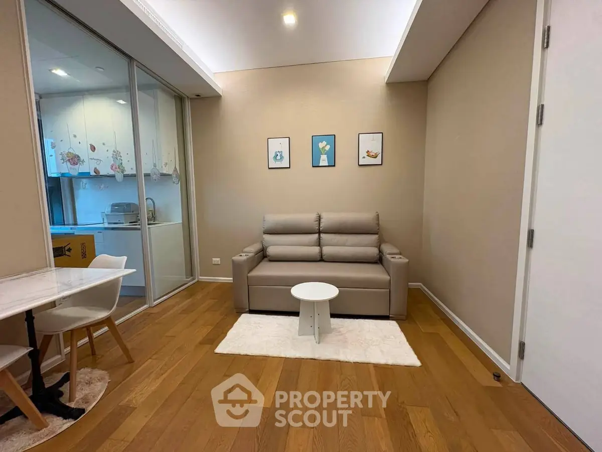 Modern living room with cozy sofa and stylish decor, adjacent to a compact kitchen area.