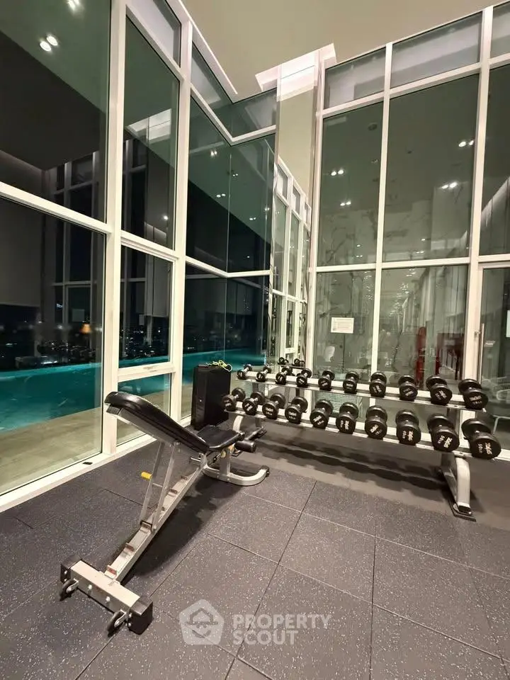 Luxurious gym with modern equipment and pool view in high-rise building