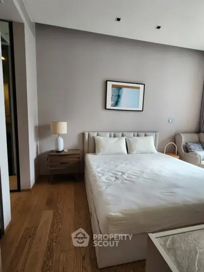 Modern bedroom with elegant decor and wooden flooring, featuring a cozy bed and stylish furniture.