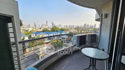 Stunning cityscape view from a spacious balcony with modern railing and outdoor seating.