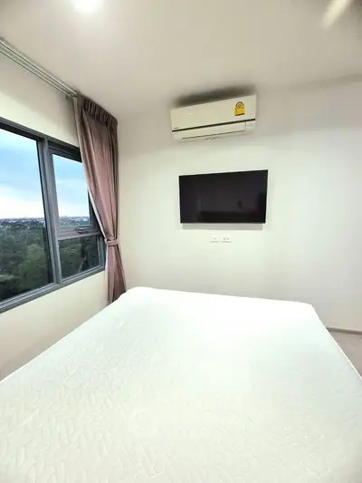 Modern bedroom with large window and wall-mounted TV, featuring a serene view.