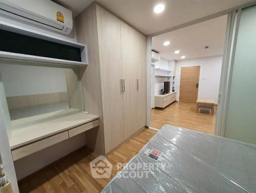 Modern bedroom with built-in wardrobe and air conditioning in stylish apartment.