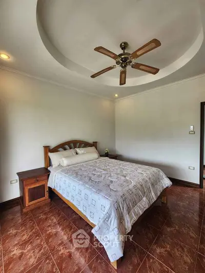 Spacious bedroom with elegant ceiling fan and cozy wooden furniture