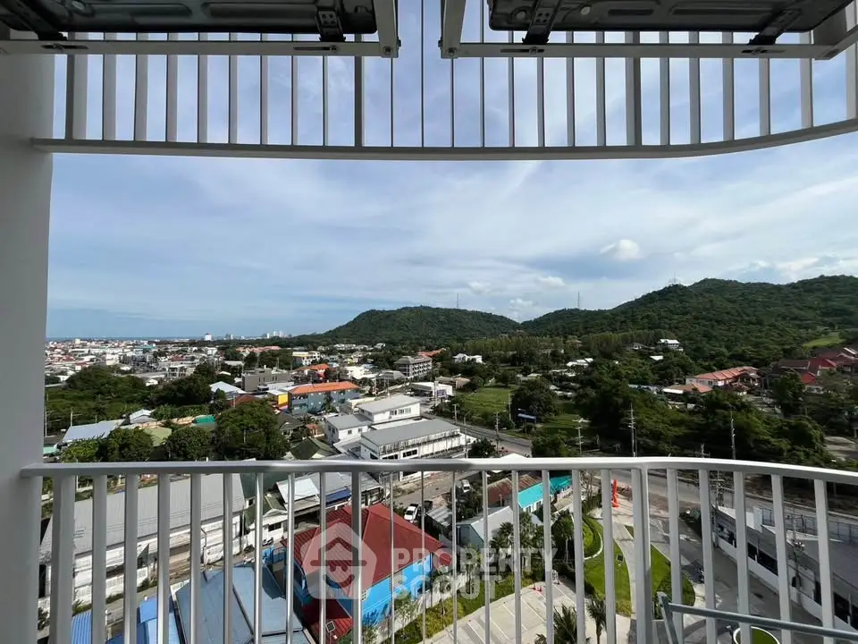 Stunning balcony view overlooking lush green hills and vibrant cityscape.