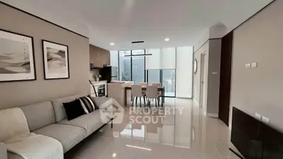 Modern open-plan living room with sleek kitchen and dining area, featuring contemporary decor and ample natural light.