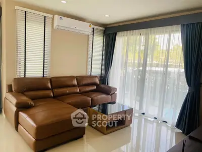 Spacious living room with leather sofa and large windows for natural light.