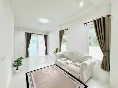 Spacious living room with elegant sofa and large windows offering natural light.