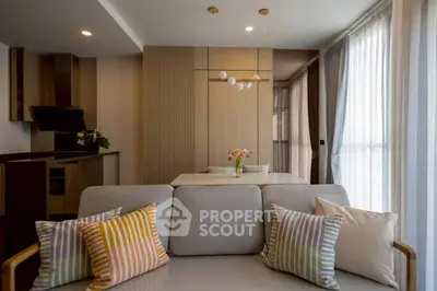 Modern living room with stylish decor and open kitchen layout, featuring elegant lighting and cozy seating.