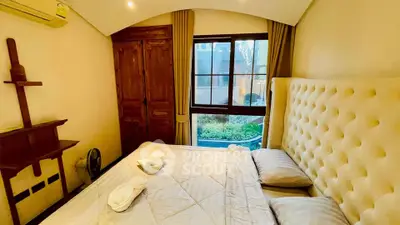 Cozy bedroom with plush headboard and garden view, perfect for relaxation.