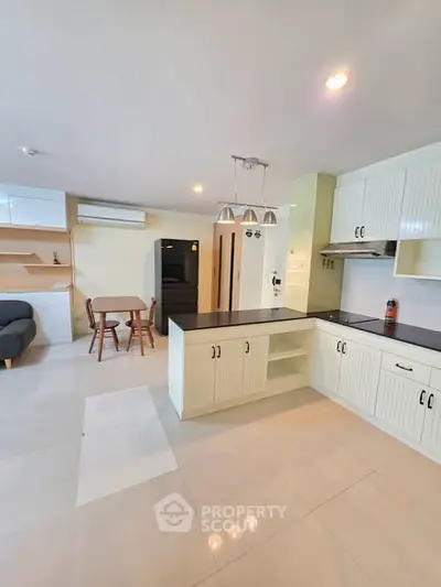 Spacious open-layout kitchen with modern appliances and dining area in a bright, airy apartment.