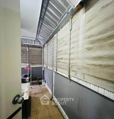 Narrow enclosed balcony with corrugated metal roof and wooden paneling