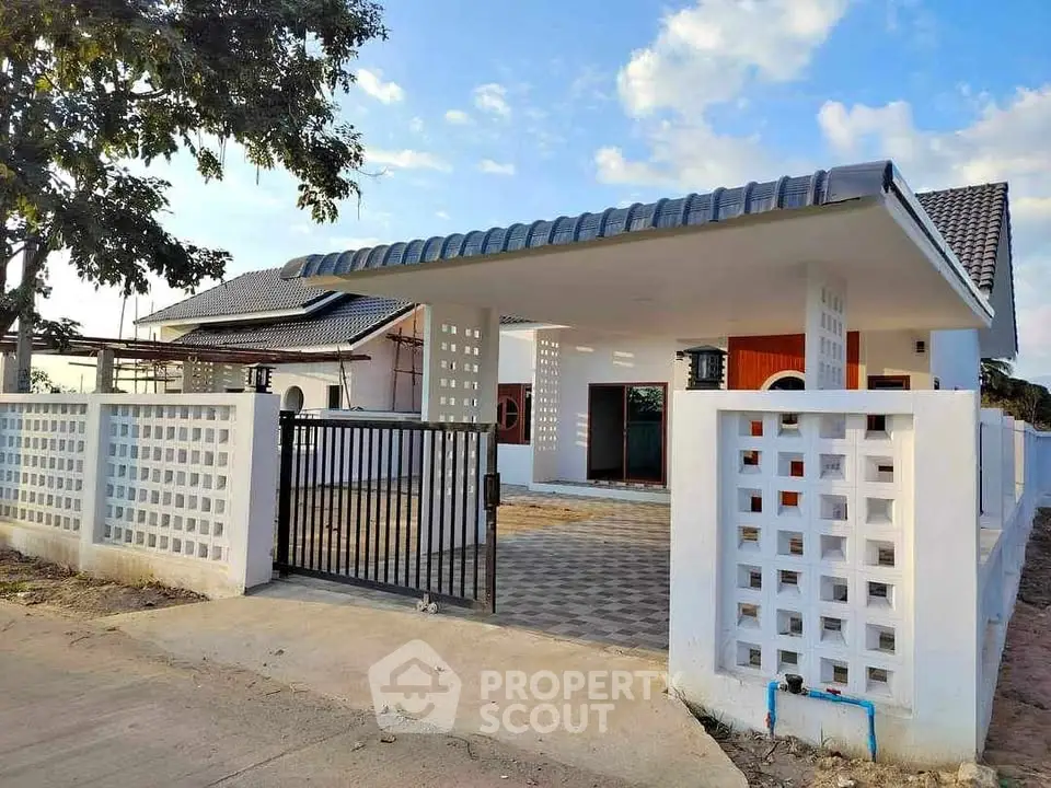 Charming modern house with gated entrance and spacious driveway under a blue sky.
