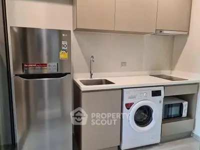 Modern kitchen with sleek appliances including fridge, washing machine, and microwave in compact layout.