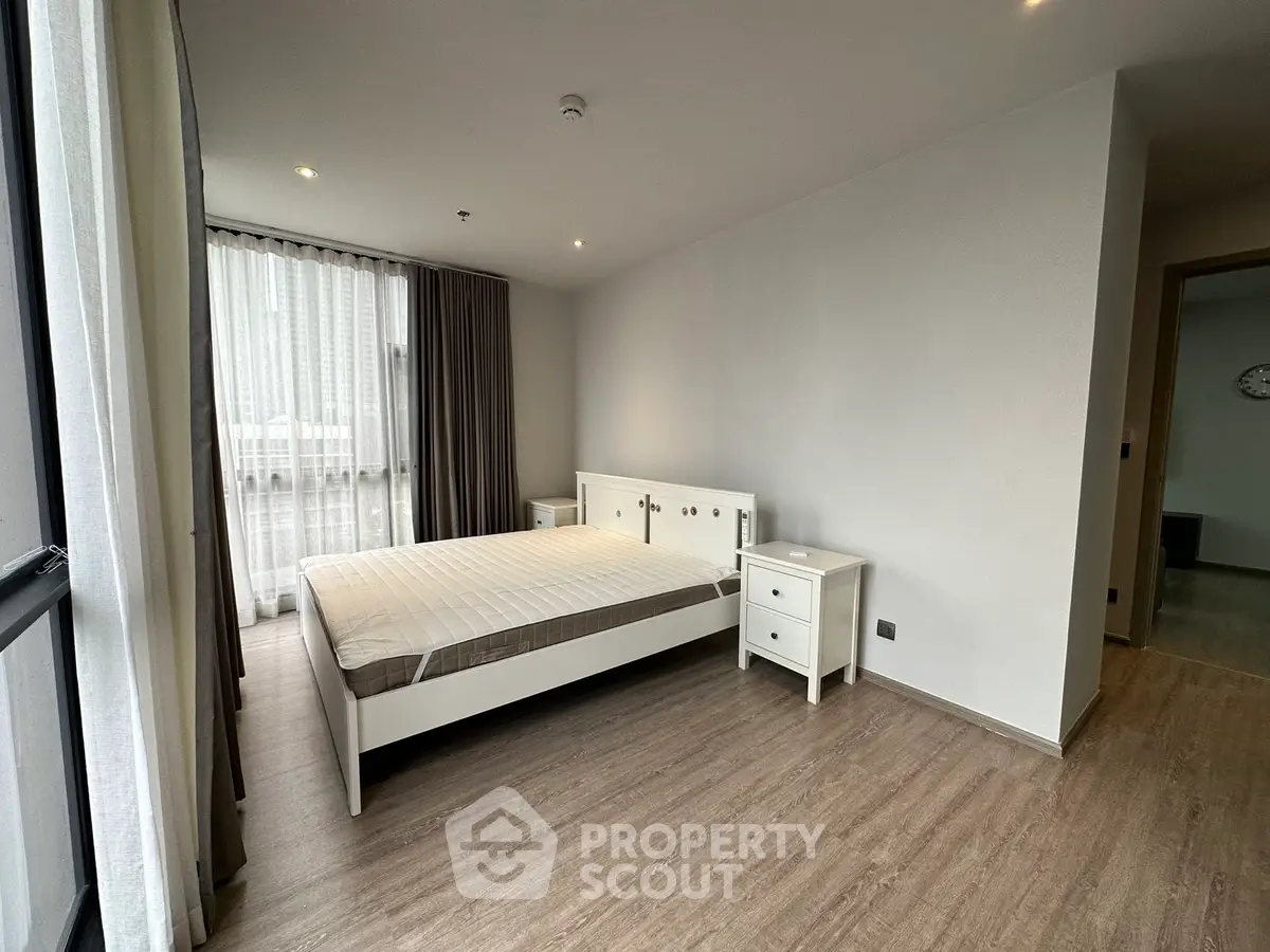 Spacious modern bedroom with large windows and minimalist furniture in a stylish apartment.