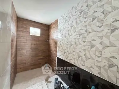 Modern bathroom under construction with stylish geometric tiles and wooden accents.
