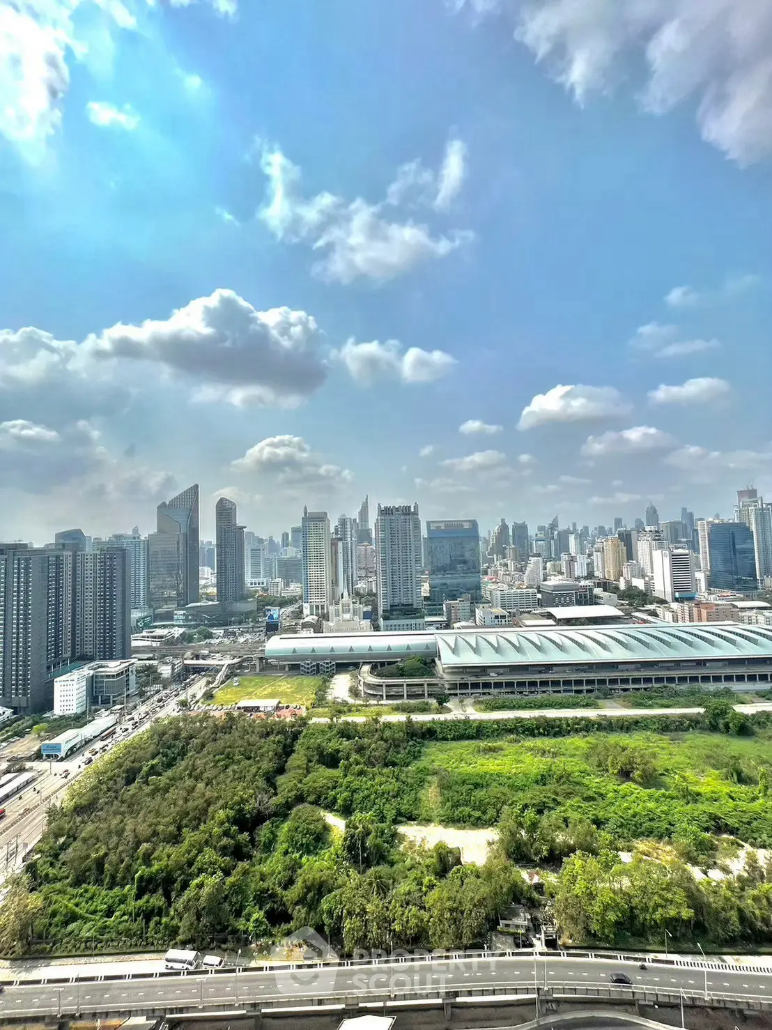 Stunning cityscape view from high-rise building with lush greenery and modern skyline.