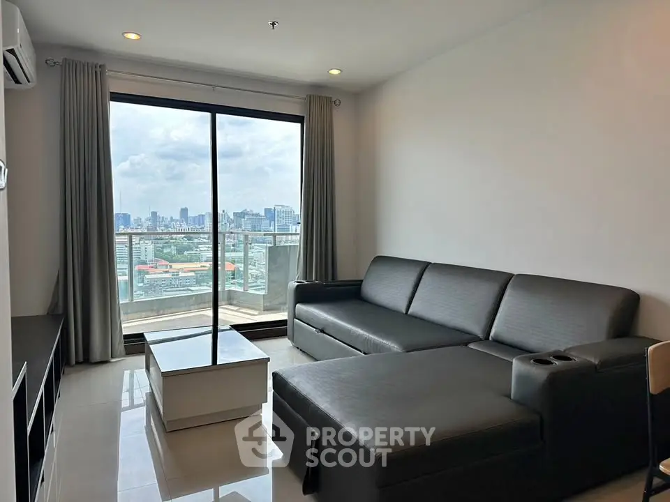 Modern living room with city view, featuring sleek black sofa and large glass doors leading to balcony.