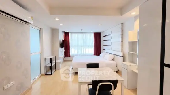 Modern studio apartment with open layout and stylish decor, featuring a cozy bed and dining area.