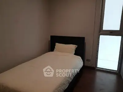 Cozy minimalist bedroom with single bed and large window, perfect for serene living.