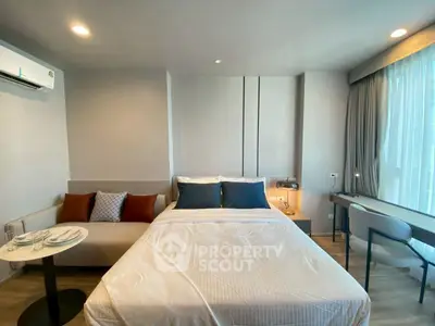 Modern bedroom with cozy seating area and large window in stylish apartment