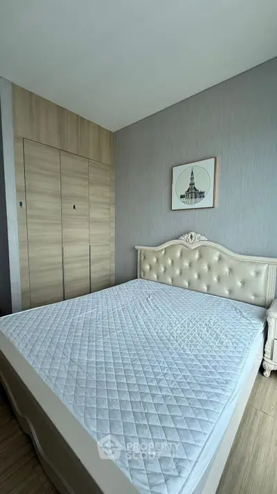 Spacious bedroom with elegant bed and built-in wardrobe in modern apartment.