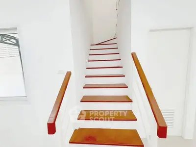 Modern minimalist staircase with wooden steps and white walls in a bright interior space.