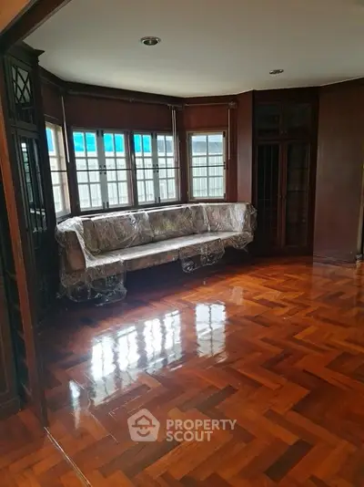 Spacious living room with polished wooden floors and large windows, perfect for natural light.