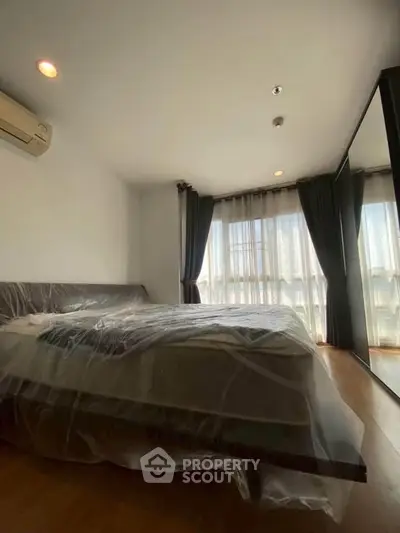 Spacious bedroom with large windows and modern furnishings, perfect for comfort and relaxation.
