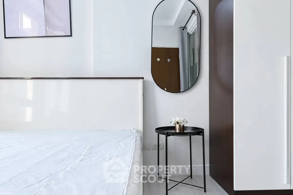 Modern bedroom with minimalist decor, featuring a sleek mirror and stylish side table.