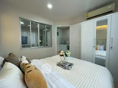 Cozy bedroom with modern decor and adjacent kitchenette in a stylish apartment.