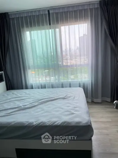 Spacious bedroom with large window offering cityscape views, featuring modern curtains and sleek flooring.