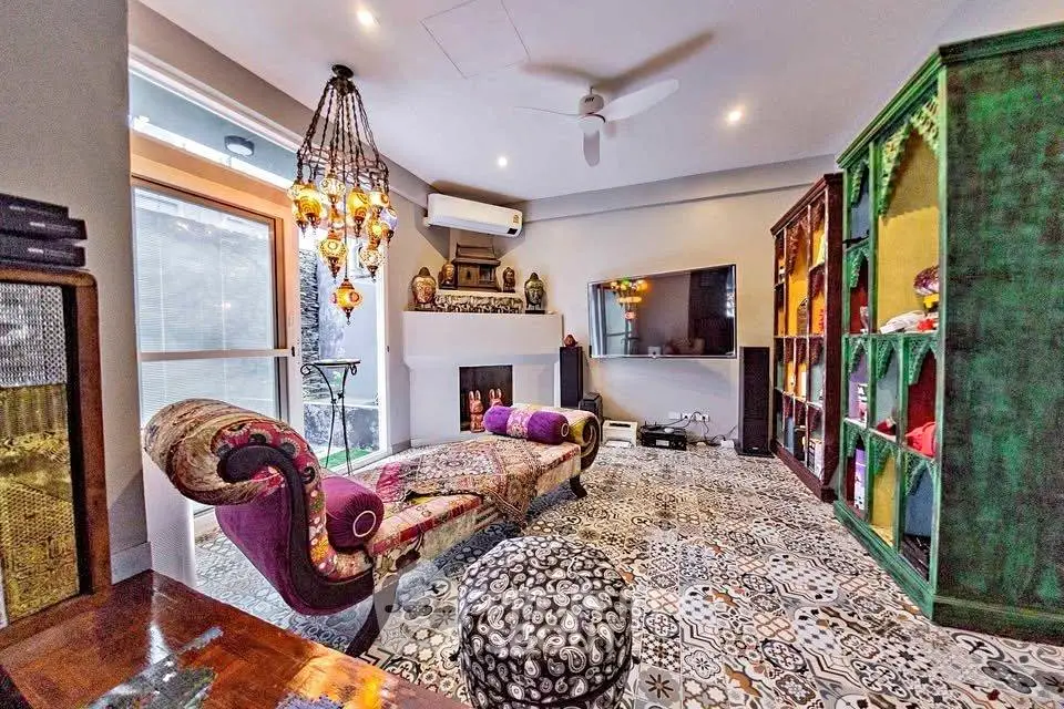 Luxurious living room with eclectic decor and vibrant colors, featuring a stylish chaise lounge and patterned flooring.