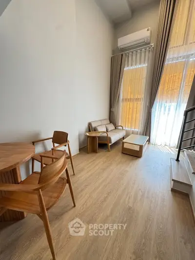 Modern living room with high ceiling, wooden flooring, and stylish furniture in a bright apartment.