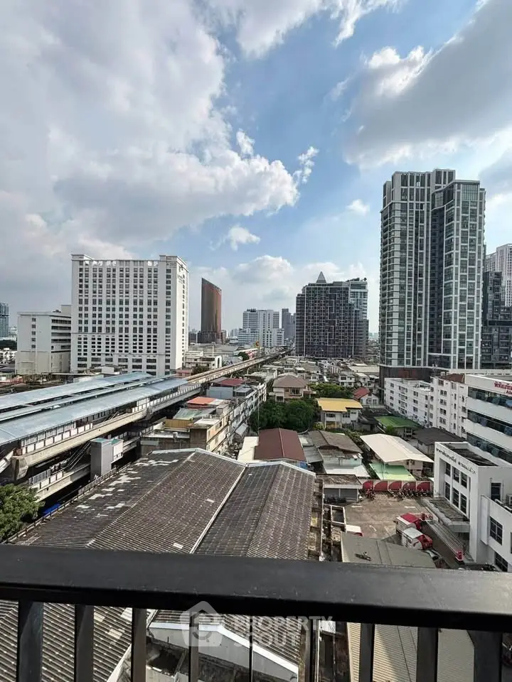 Stunning cityscape view from a high-rise balcony overlooking urban skyline and train tracks.