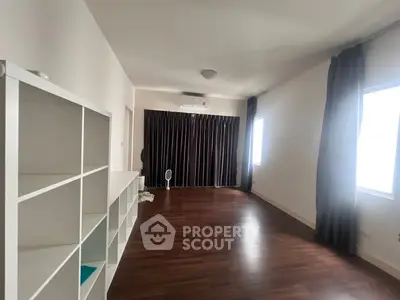 Spacious room with wooden flooring and large windows, ideal for versatile living space.