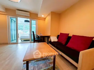 Spacious living room with modern decor and natural light, leading to a cozy bedroom with scenic views.