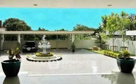 Luxurious driveway with elegant fountain and lush greenery in upscale residential property.