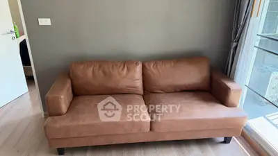 Modern living room with brown leather sofa and large window view.