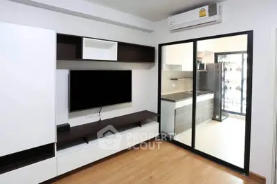 Modern living room with sleek entertainment unit and view into stylish kitchen